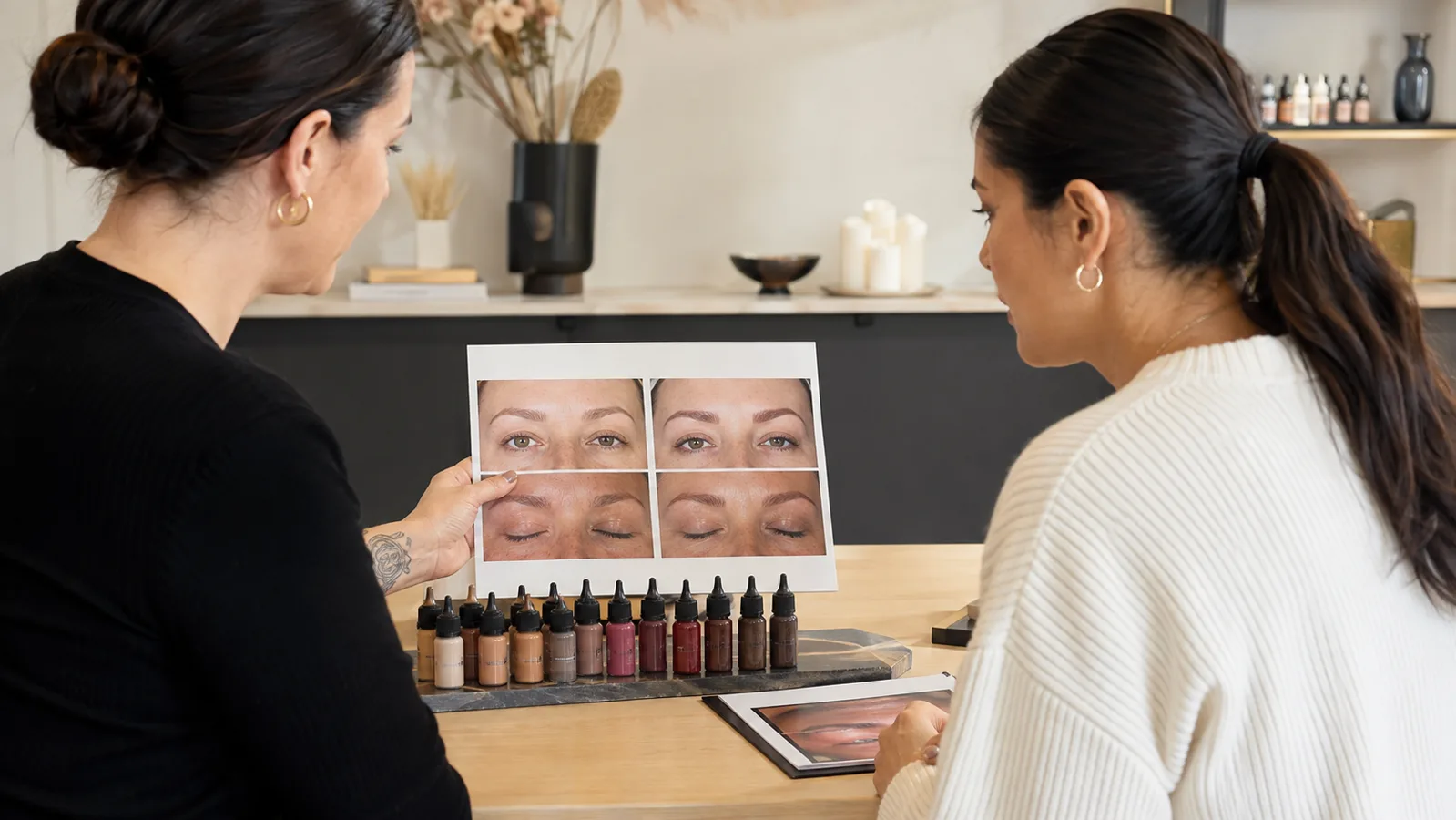 Body art artist and client reviewing healed colour results beside pigment samples